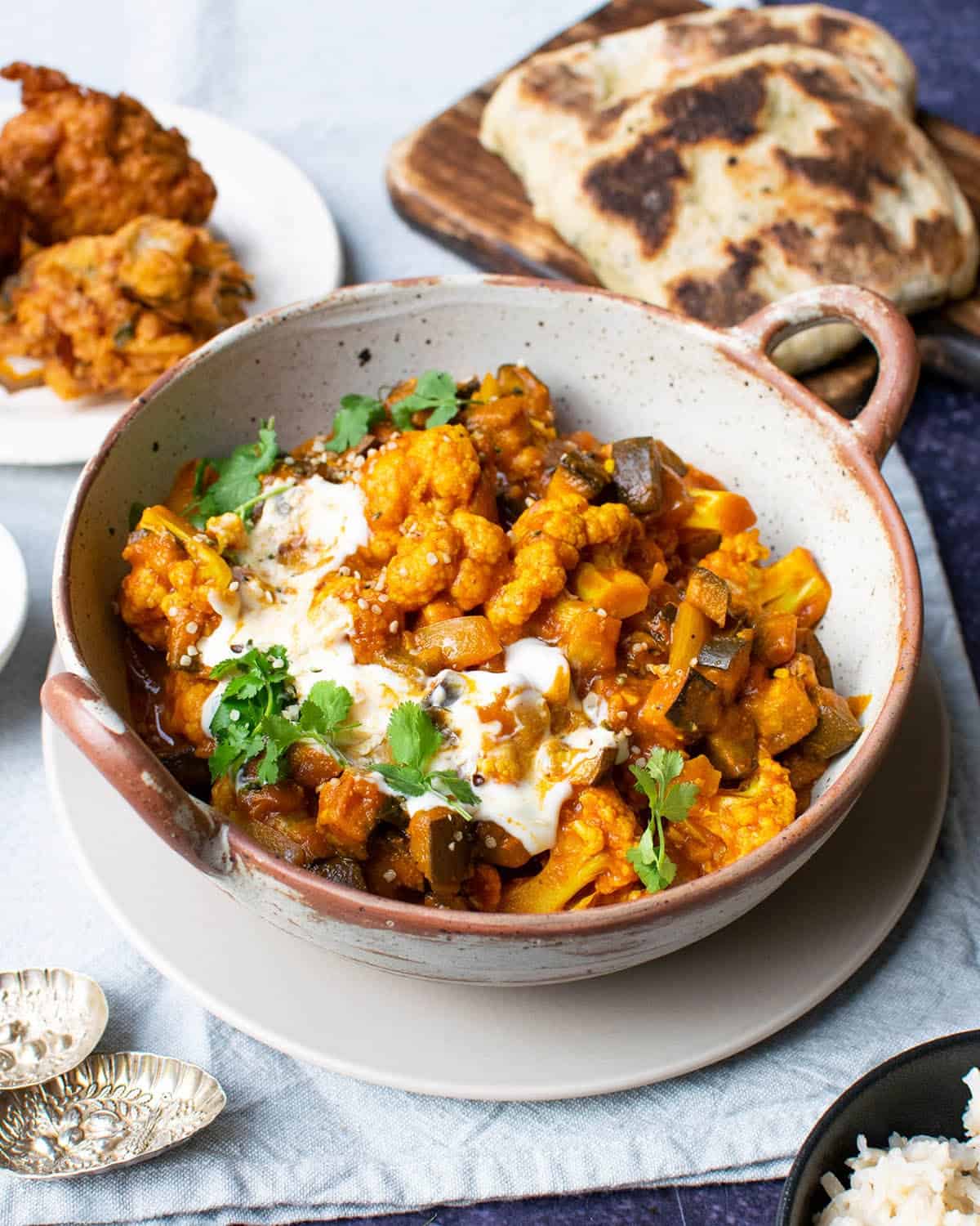 Aubergine and cauliflower curry served with yoghurt, fresh coriander and naan bread.