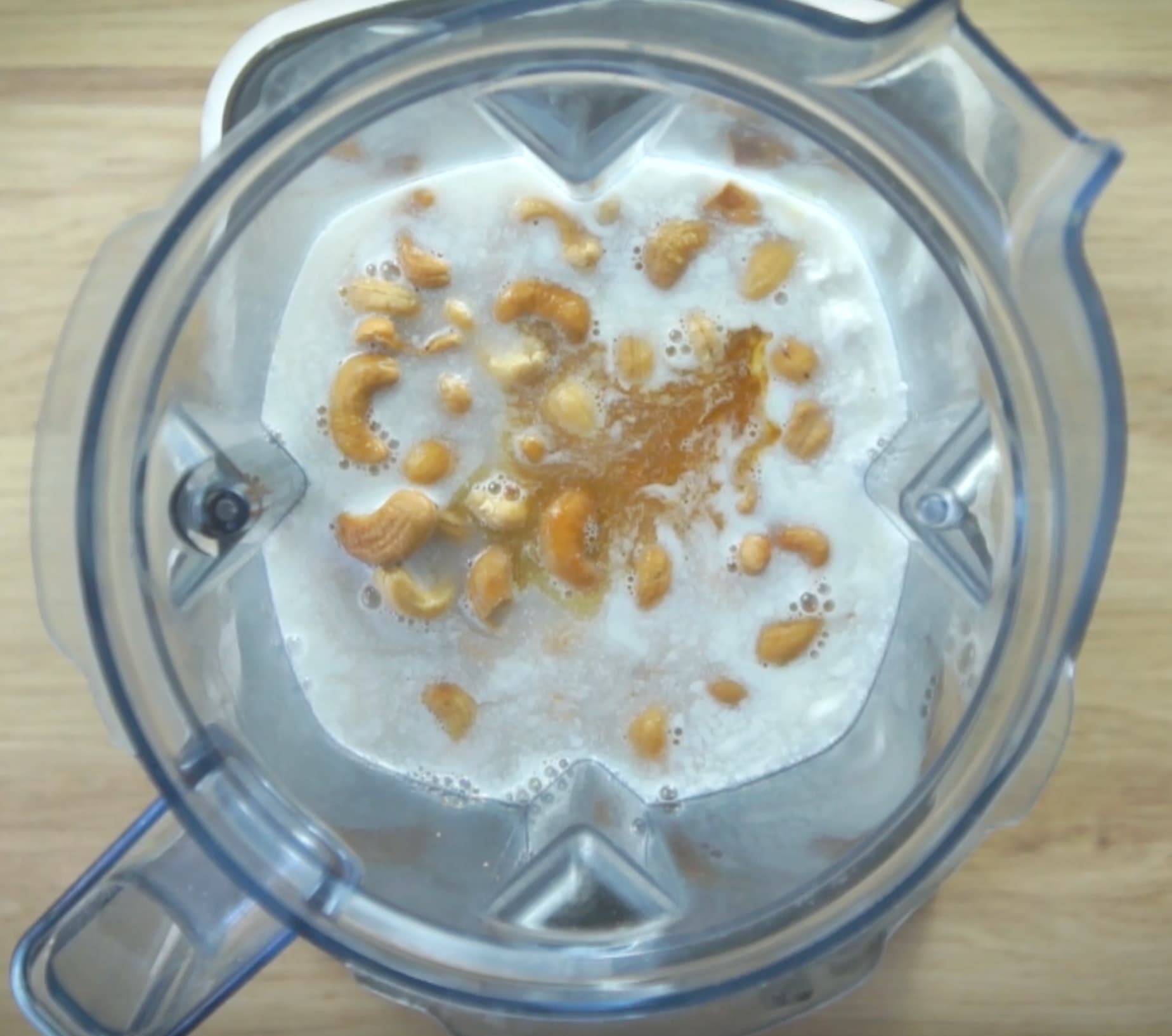 Blender with cashews in a white liquid.