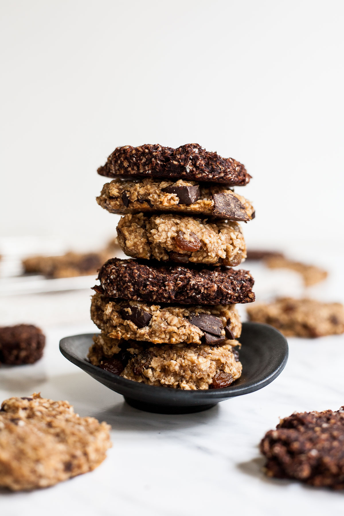 Stack of brown and dark brown oatmeal chocolate cookies on a small black bowl.