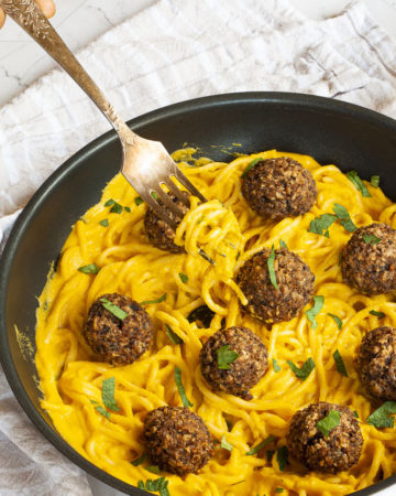 Yellow pasta sauce in a frying pan topped with mushroom meatballs.