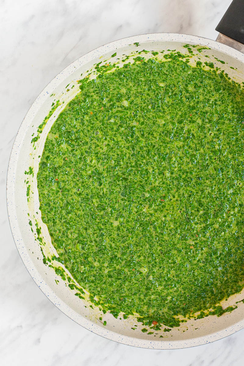 A white frying pan from above with green sauce