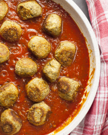 Overlay photo of a frying pan. Lot of small eggplant balls in marinara sauce