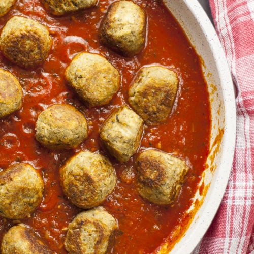 Overlay photo of a frying pan. Lot of small eggplant balls in marinara sauce