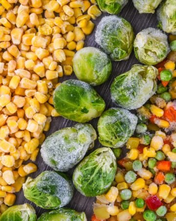 Frozen vegetables unpacked like corn, green beans, Brussels sprouts, broccoli, and mixed veggies