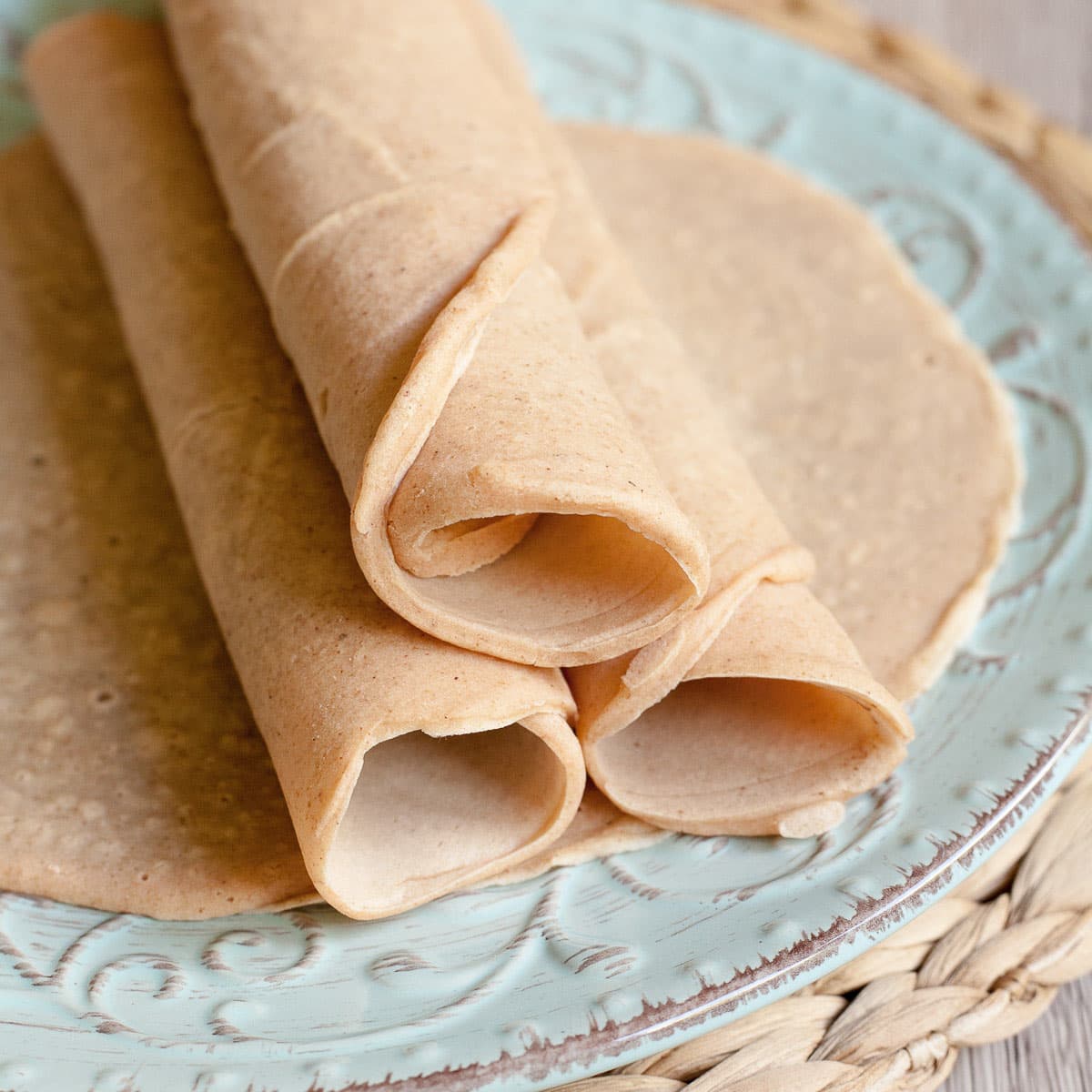 3 rolled tortillas on top of one flat placed on a light blue plate