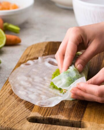A hand is rolling a filling instead a rice paper wrapper.