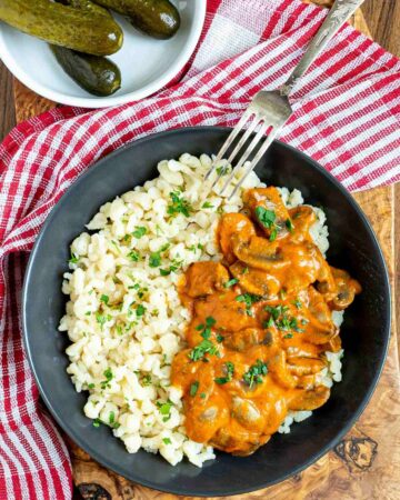 Hungarian mushroom stew over nokedli in a black bowl with a fork on the side.