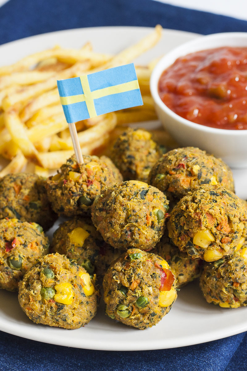 Small brown balls with yellow, red, green pieces placed on top of each other to form a hill. A blue and yellow flag is stuck in one of them.