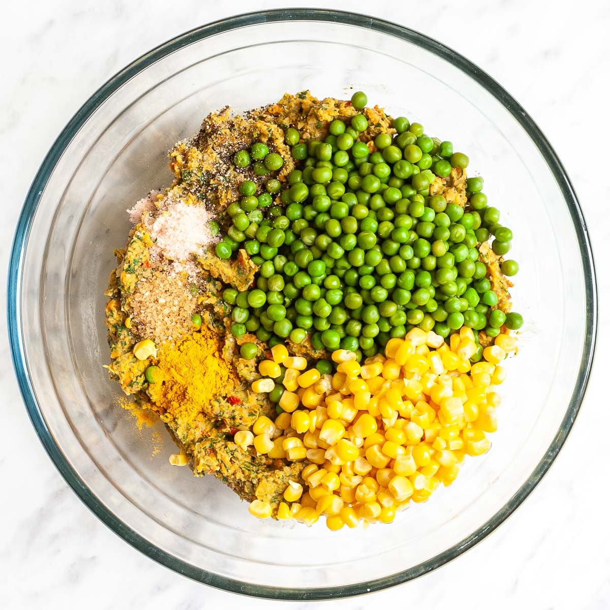 Glass bowl with corn, green peas, spices and crumbly veggie puree