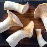 trumpet shaped king oyster mushrooms on a wooden board