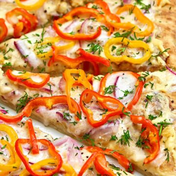 Pizza slices with melted cheese, red and orange pepper slices and dried herbs on top