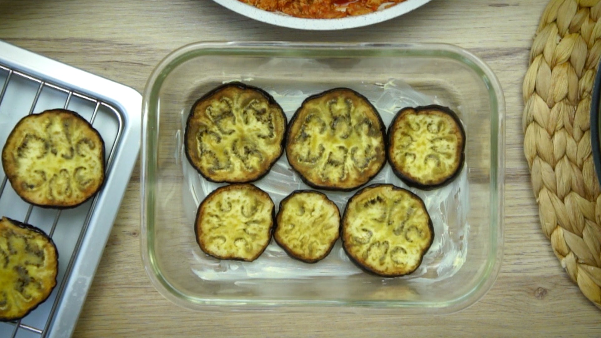 A greased rectangular glass baking dish with fried eggplant slices.