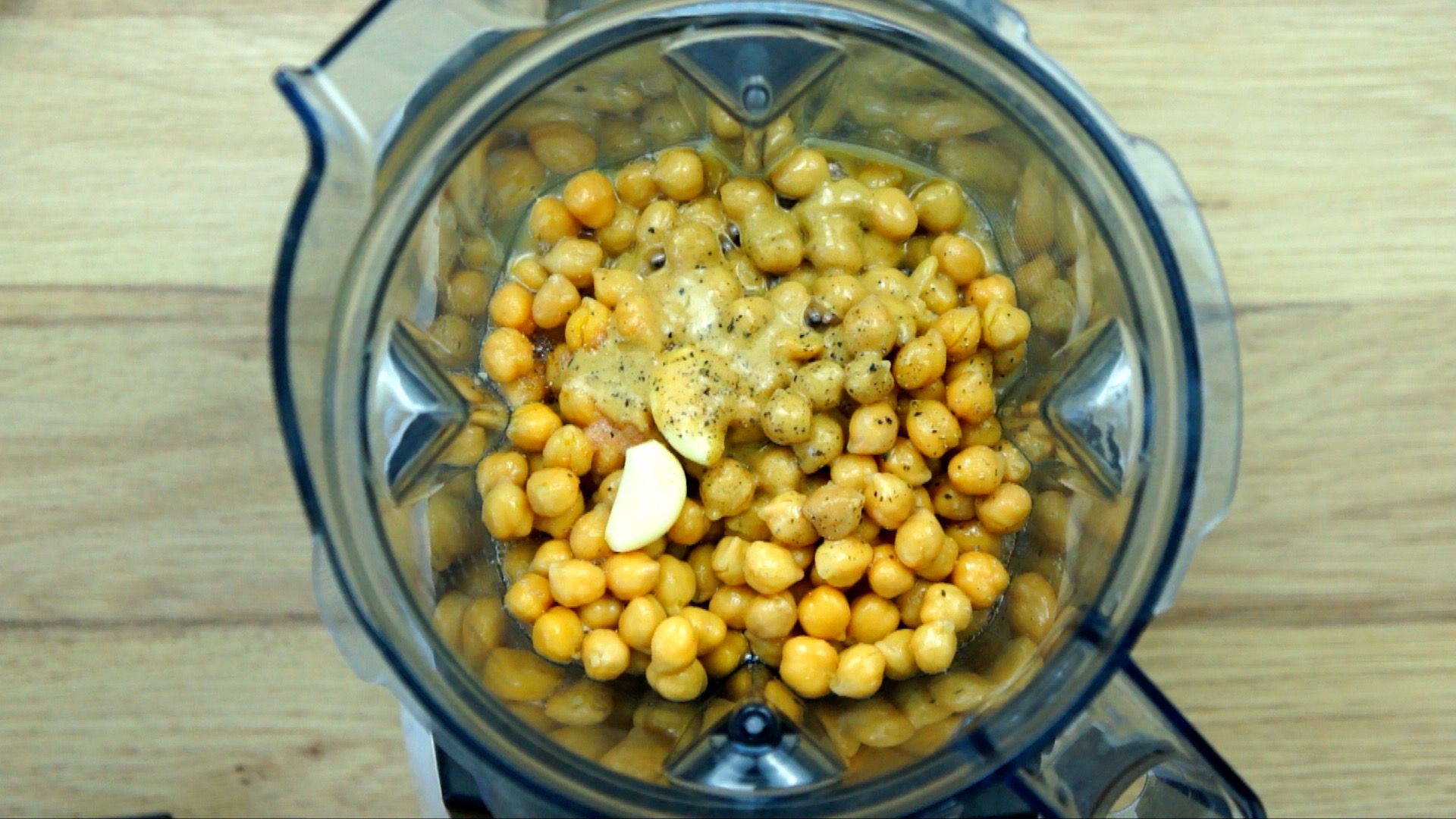 Blender from above with chickpeas, garlic clove and liquid.