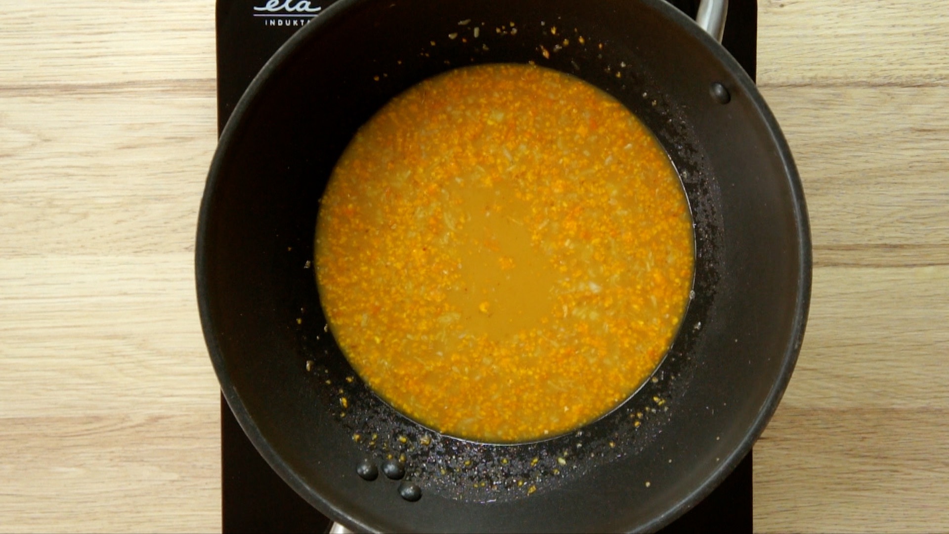 Thin orange liquid in a wok