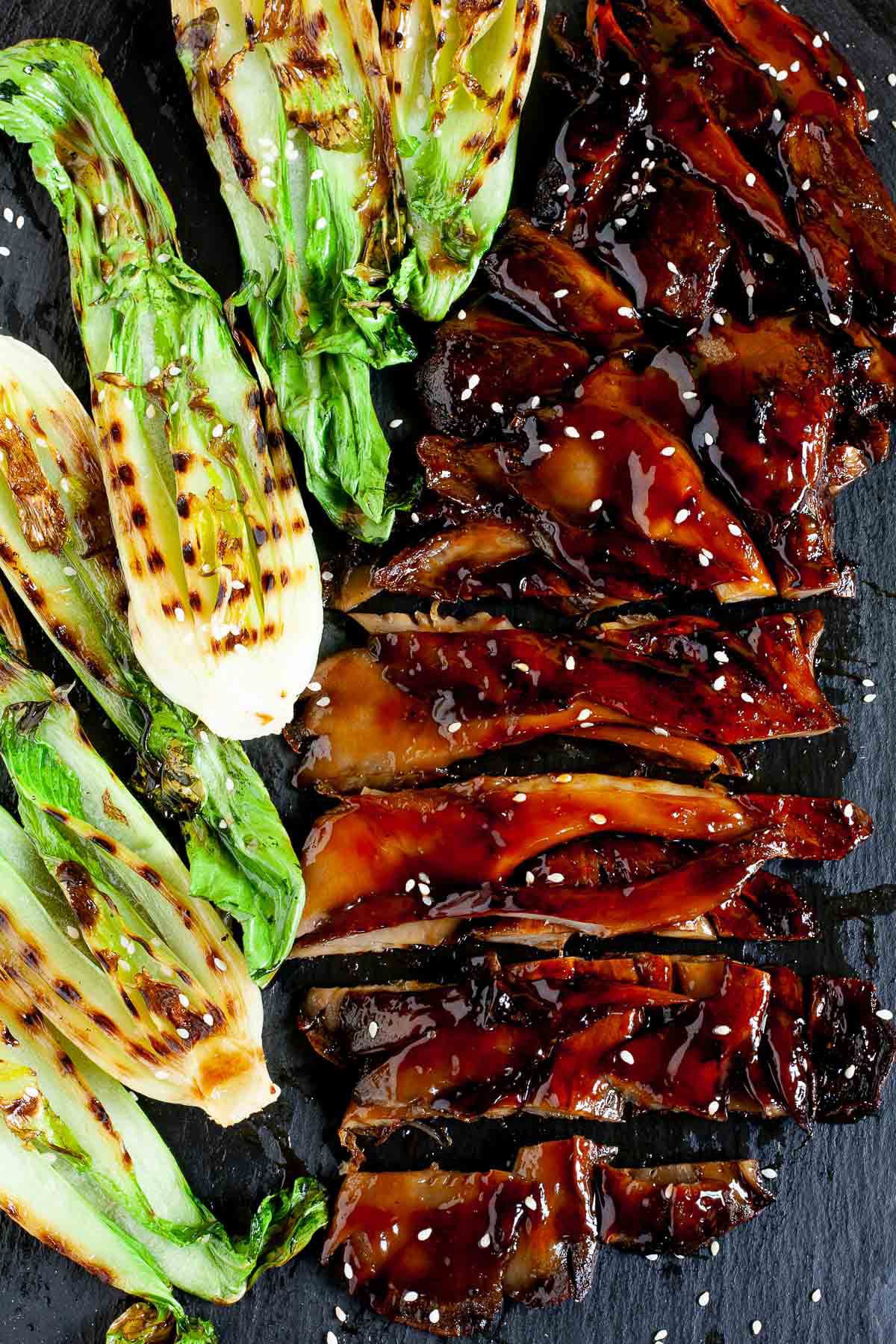 Black boardabove with crispy brown juicy flattened oyster mushroom clusters and half bok choy with charcoal stripes