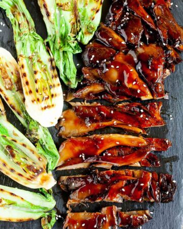 Black boardabove with crispy brown juicy flattened oyster mushroom clusters and half bok choy with charcoal stripes