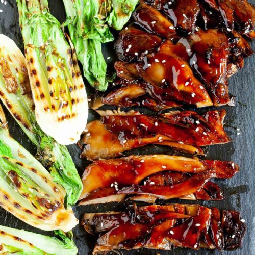 Black boardabove with crispy brown juicy flattened oyster mushroom clusters and half bok choy with charcoal stripes