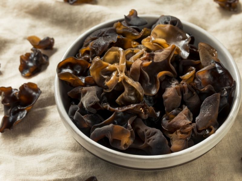 Brown raw wood ear mushrooms in a white bowl