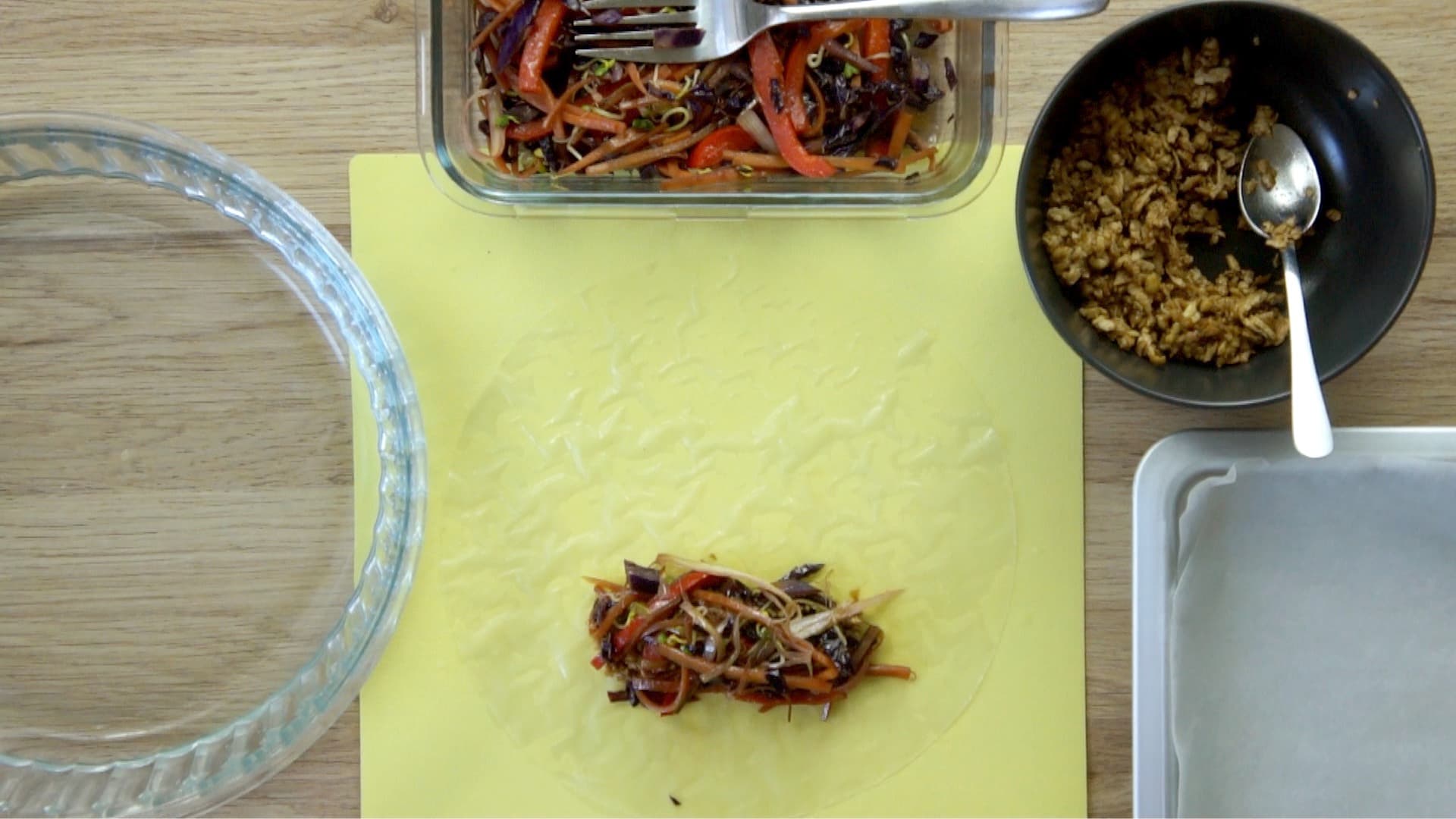A short line of shredded veggies are placed on the lower third of the rice paper. The fillings are in small bowls next to it.