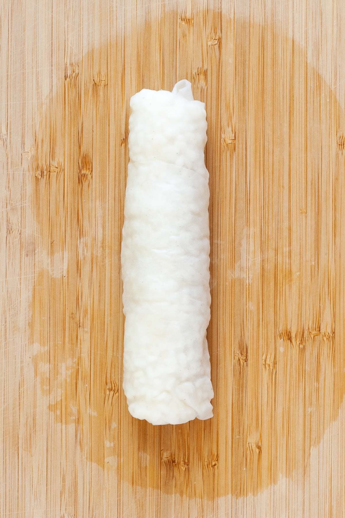 Rolled up sushi roll covered in translucent rice paper.