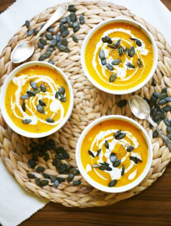 Simple Pumpkin Cream Soup from fresh Hokkaido pumpkin - 3 small bowl of pumpkin soup sprinkled with pumpkin seeds, chia seeds and dairy-free cream poured on top.