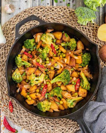 Skillet with potatoes, broccoli, chili peppers, green peas and onion. All slightly fried around the edges.