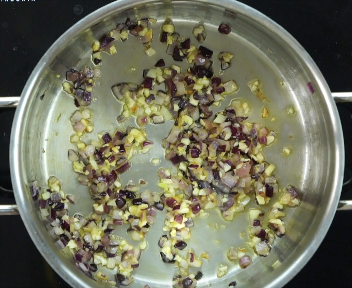 Stockpot with oil, chopped red onion and garlic.
