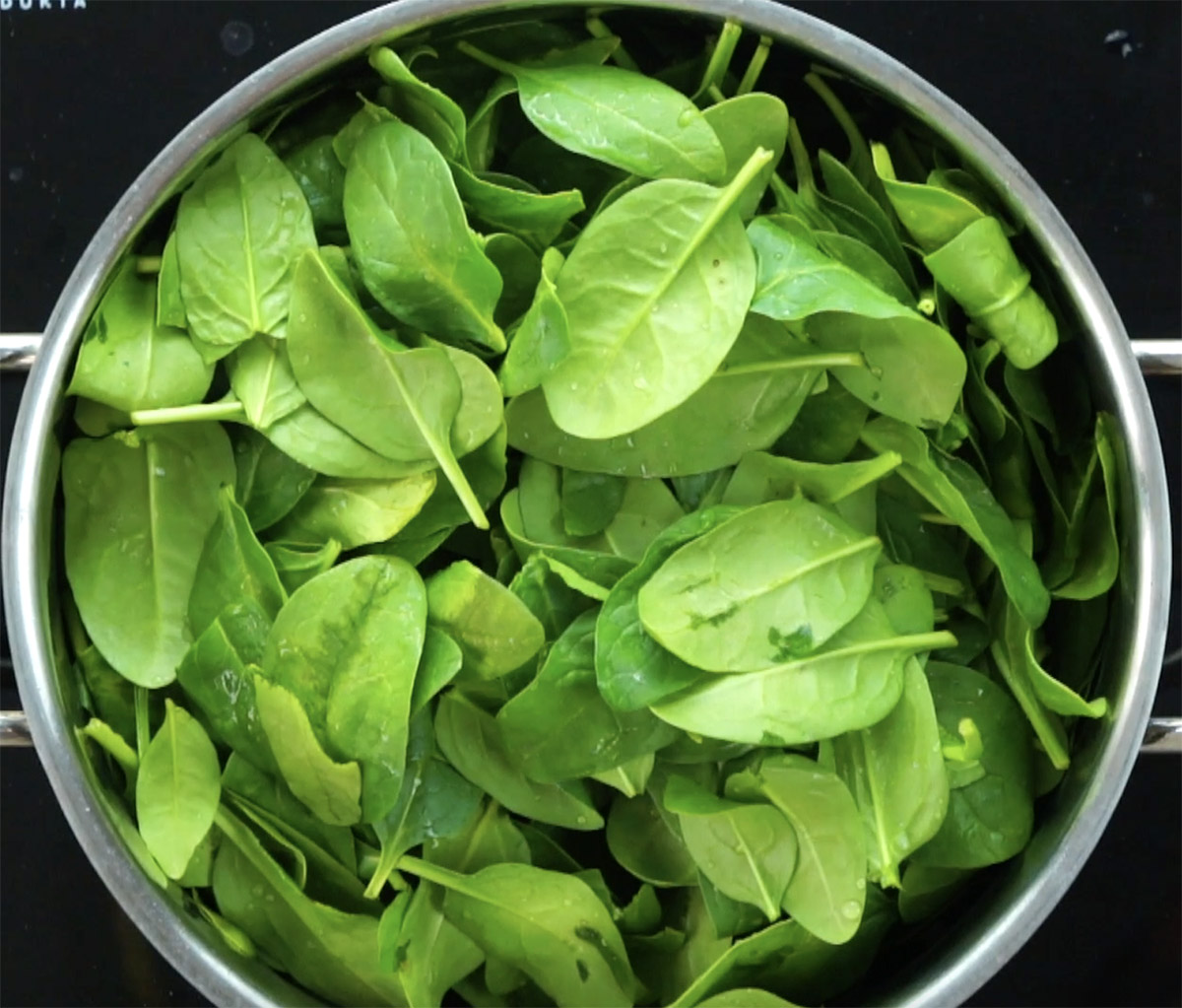 Stockpot with fresh spinach leaves.