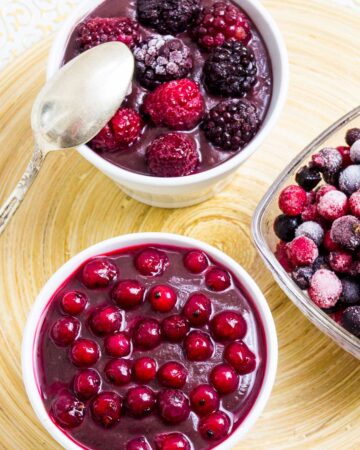 3 small bowls, one with vegan chocolate pudding topped with mixed berries, the other topped with red currant and one bowl is only fruits.