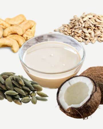 Cashews, coconut, sunflower seeds, pepitas around a small glass bowl with a light brown paste