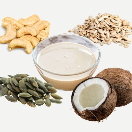Cashews, coconut, sunflower seeds, pepitas around a small glass bowl with a light brown paste