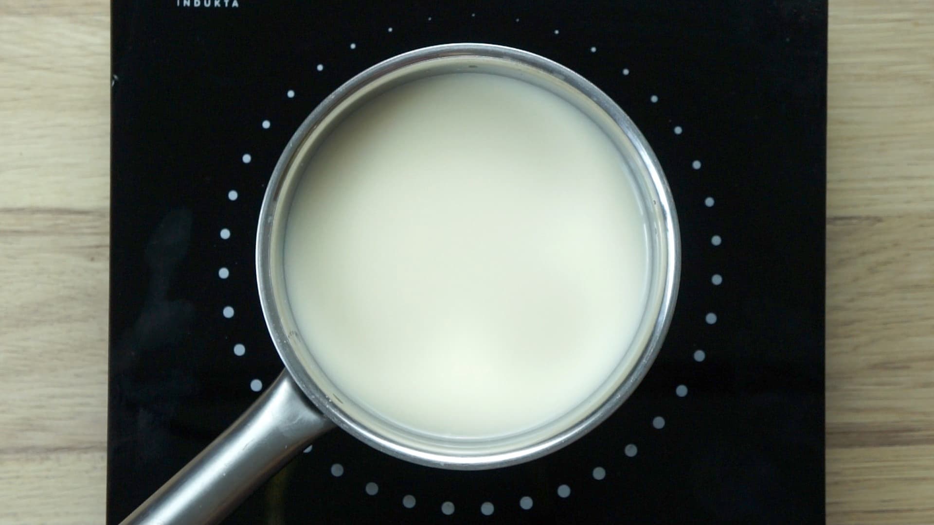 A saucepan on an induction hot plate with white liquid (milk).
