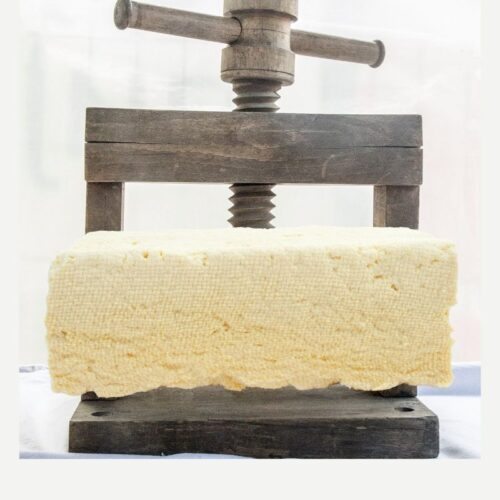 Tofu is being pressed with a wooden press