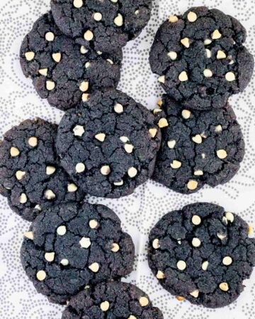 Blue-purple cookies with white chocolate chips on a white-grey surface.