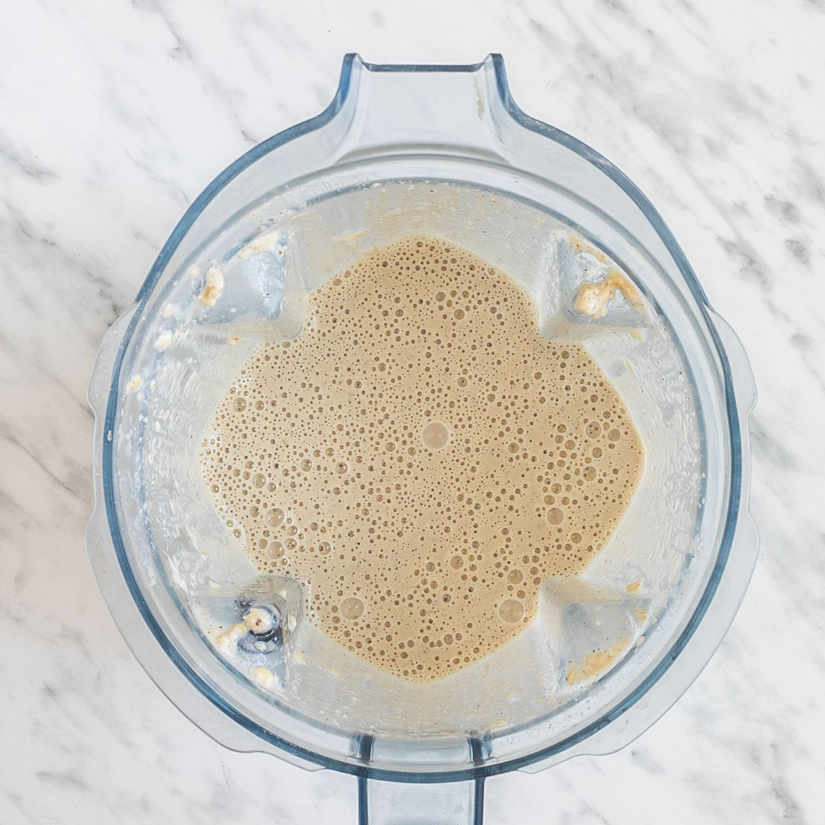A blender from above with a light brown sauce.