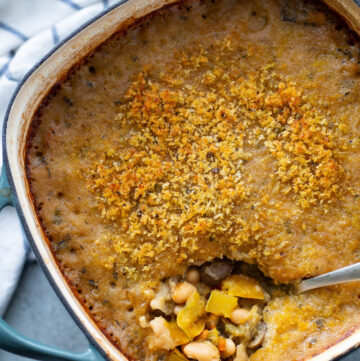 Baking dish with a veggie stew. A spoon is taking some from the corner.