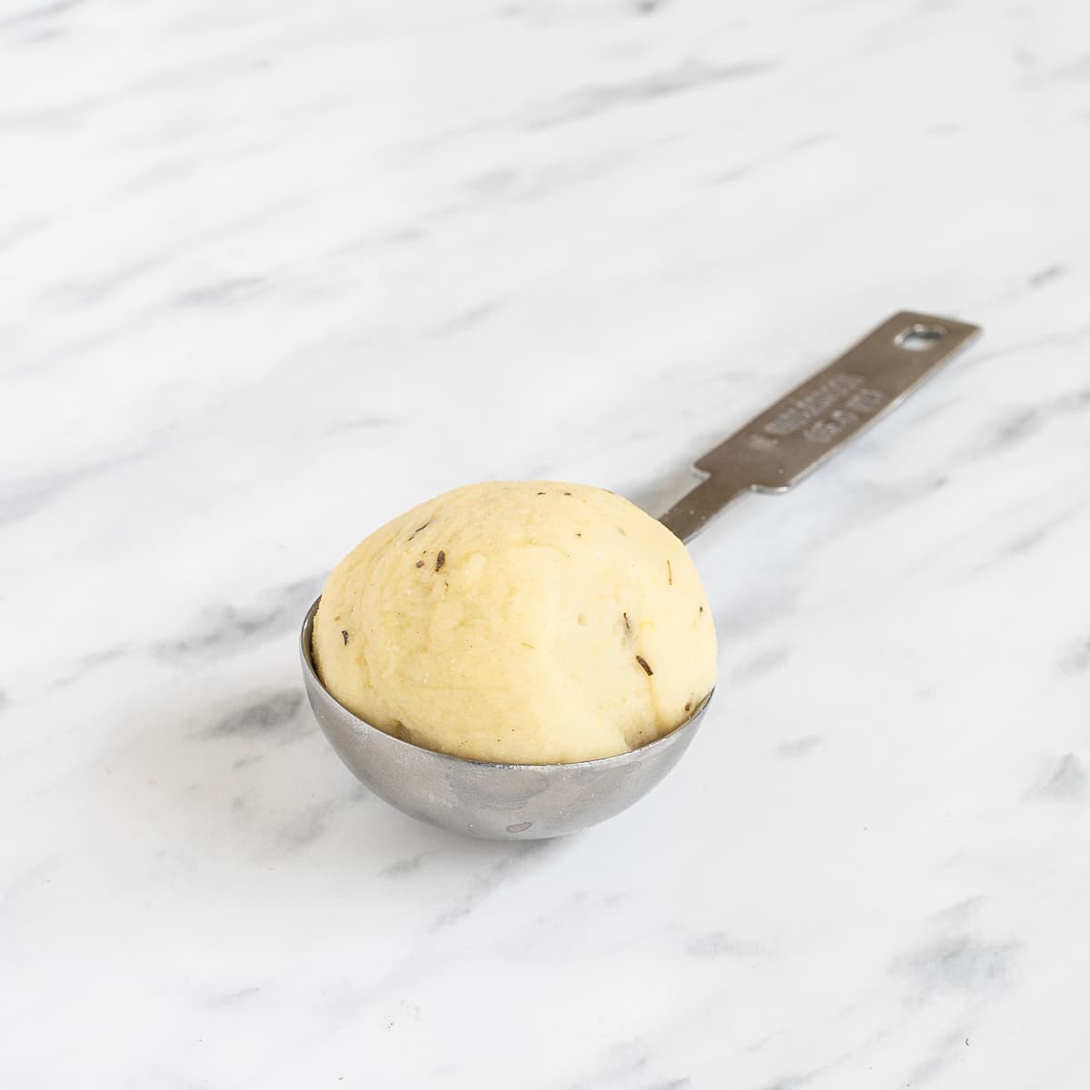 A measuring spoon for one tablespoon with a round ball of dumplings dough.