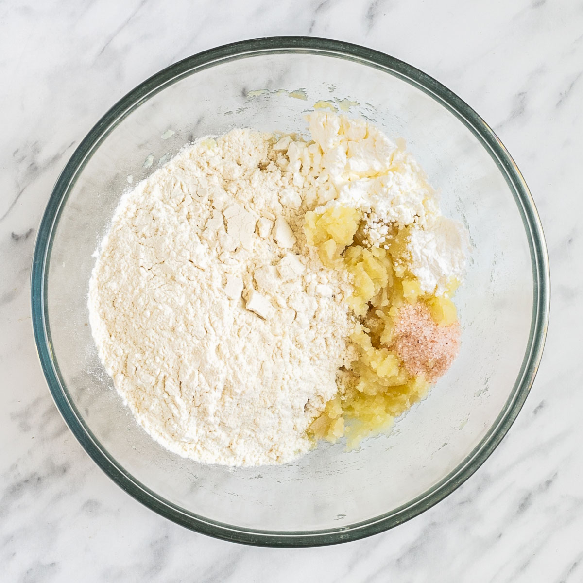 A glass bowl with flour, mashed potato and salt.
