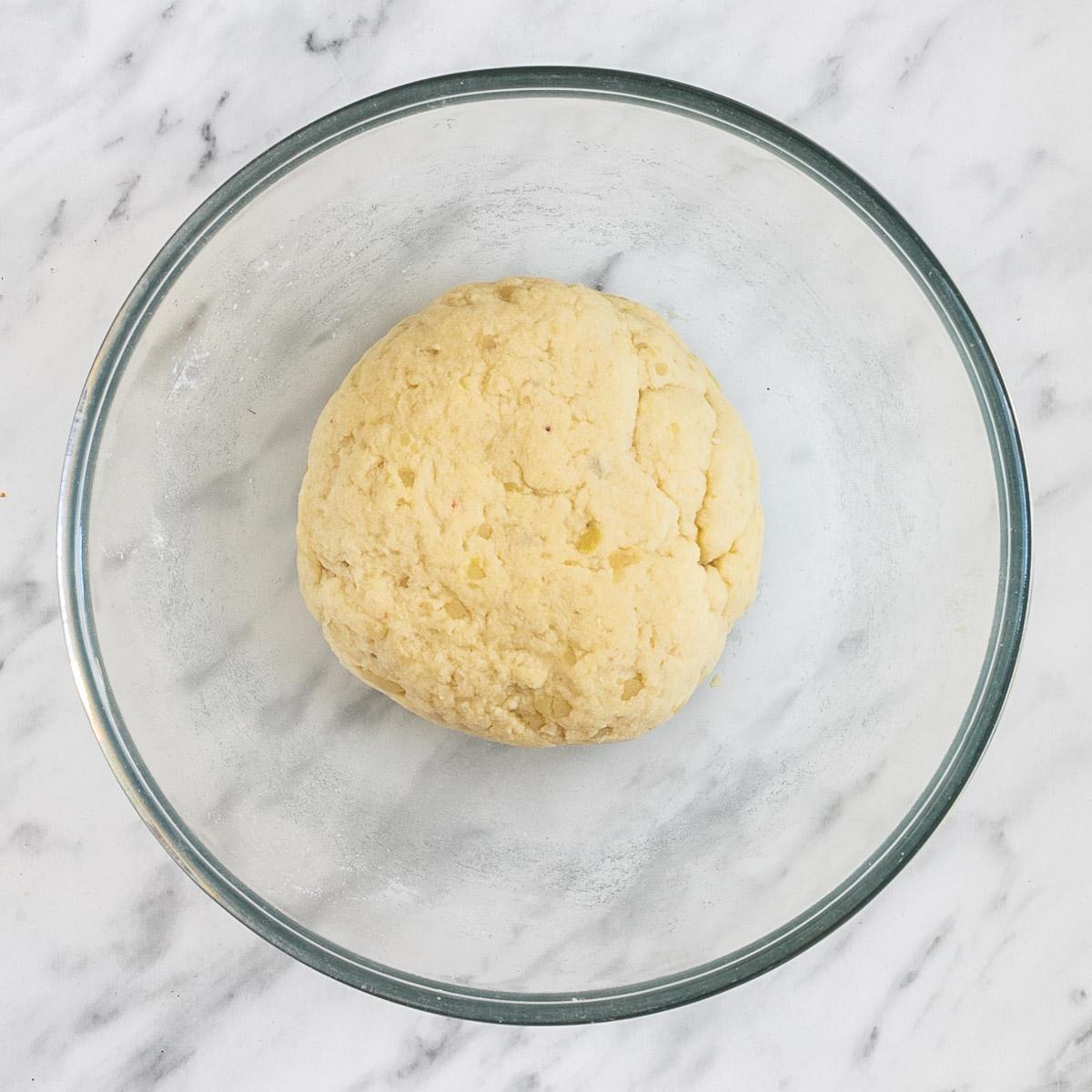 A glass bowl with a ball shaped dumpling dough.