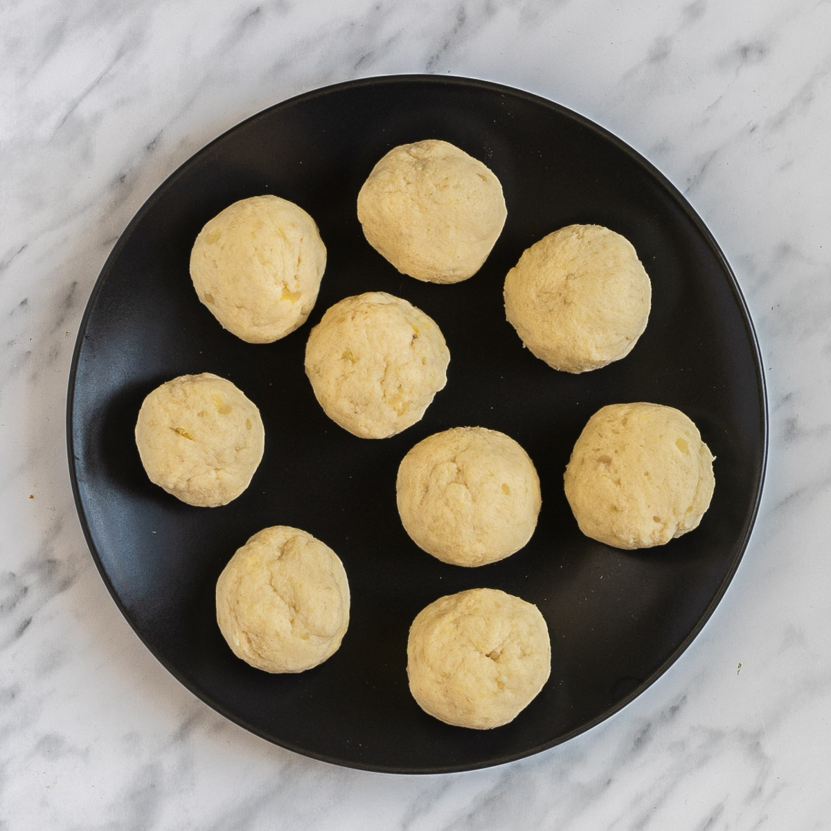 9 dumplings on a black plate.