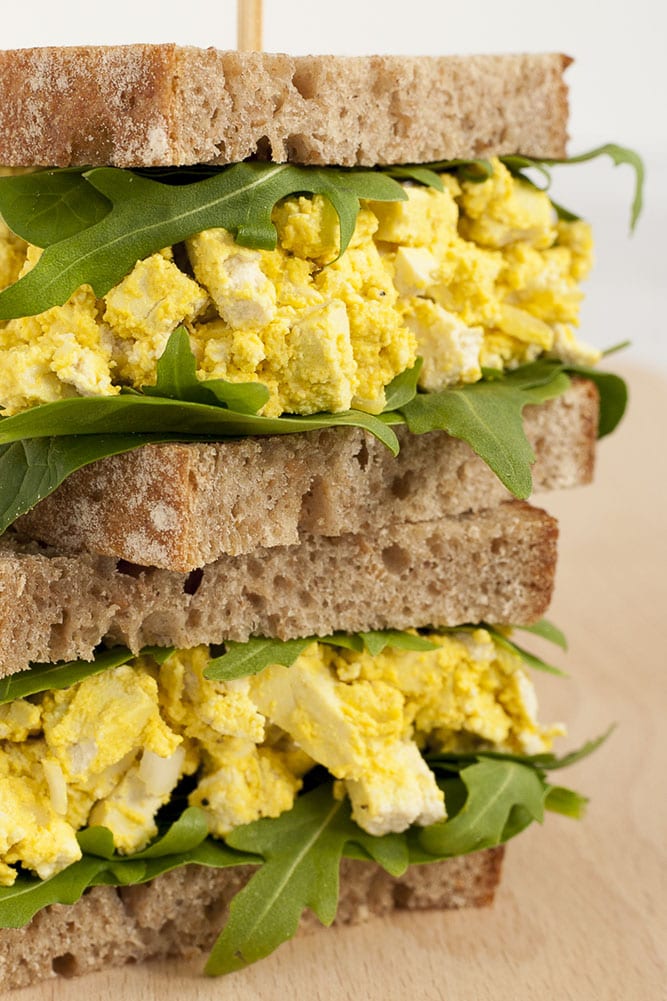 Slices brown toast bread with arugula and yellow fake egg salad