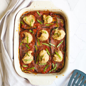 Red sauce topped with stacks of thick white paste sprinkled with freshly chopped green herbs.