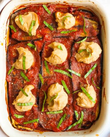 Red sauce topped with stacks of thick white paste sprinkled with freshly chopped green herbs.