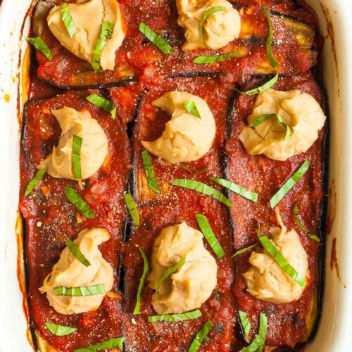 Red sauce topped with stacks of thick white paste sprinkled with freshly chopped green herbs.