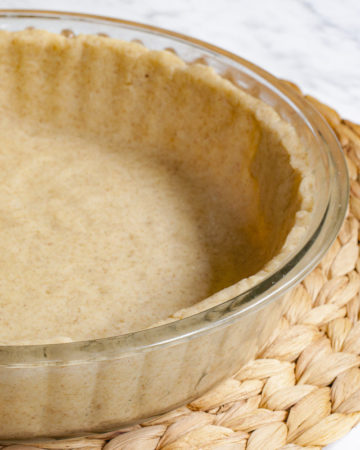 Glass pie pan with brown unbaked pie crust from the side