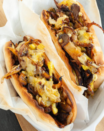 2 bread loaves stuffed with brown mushroom shreds and melted cheese wrapped in a white paper.