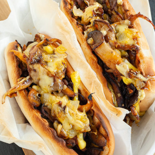 2 bread loaves stuffed with brown mushroom shreds and melted cheese wrapped in a white paper.