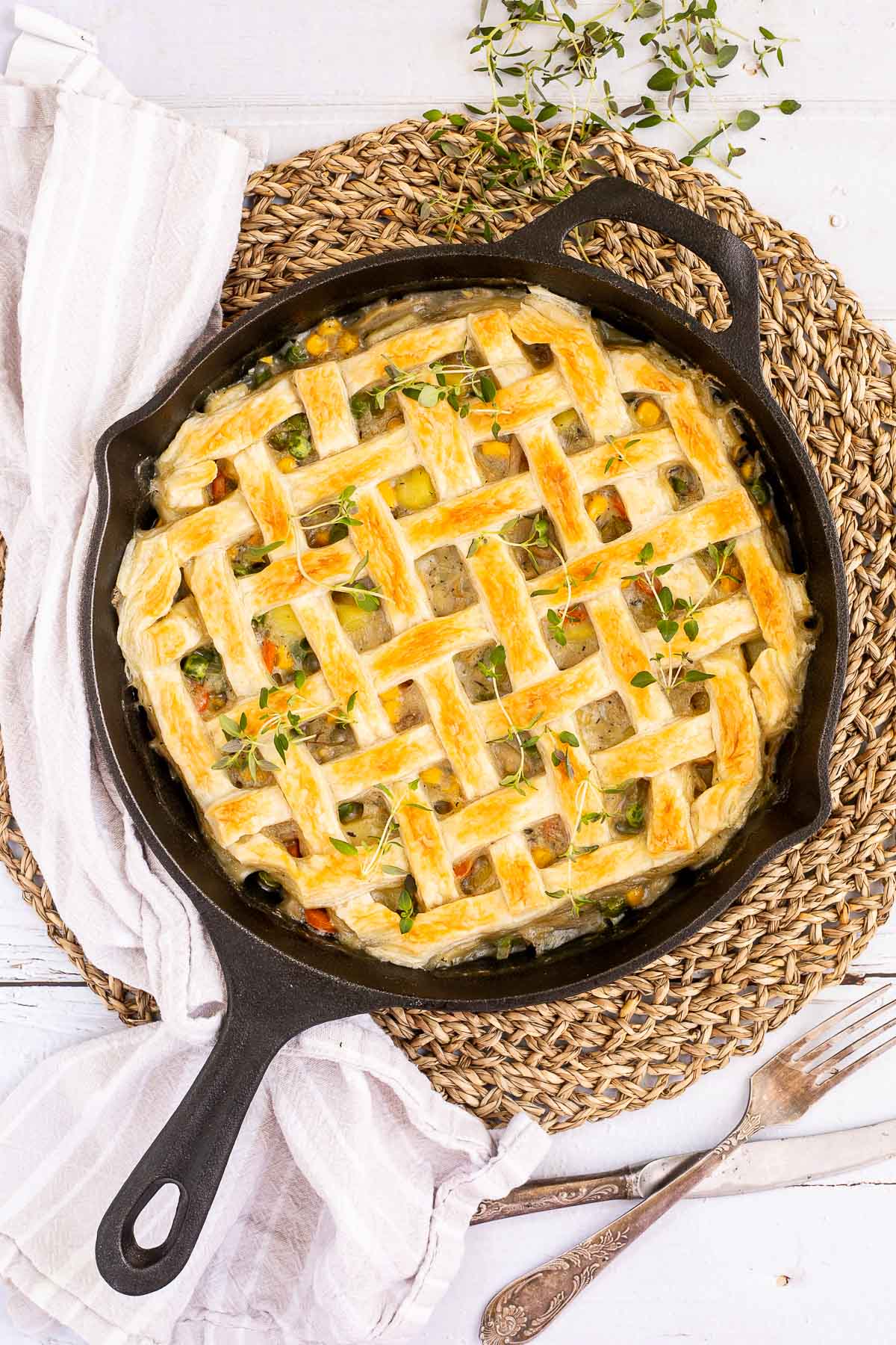 Cast iron skillet with veggie stew topped with puff pastry in a lattice pattern. 