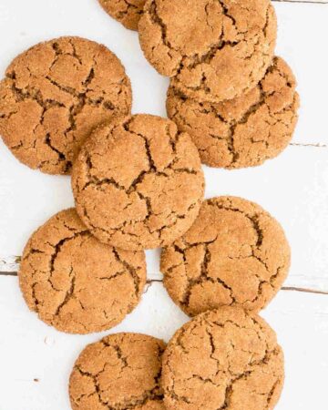 Light brown cookies with crinkled top on a white wooden surface.