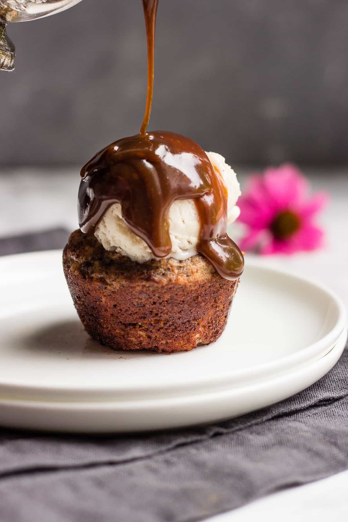 A cupcake is being drizzled with caramel sauce.